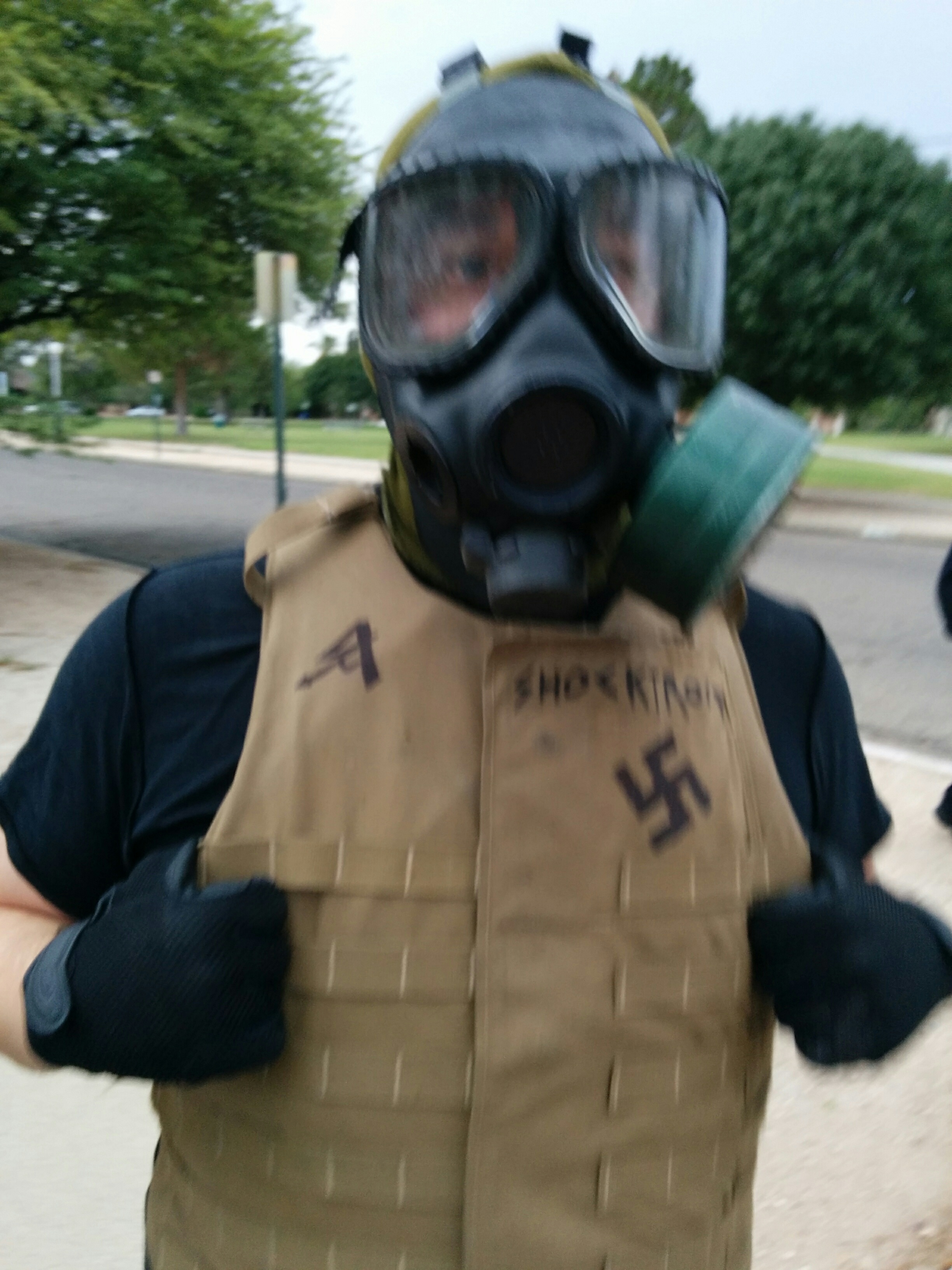 Close up of the Nazi in the gas mask, showing a swastika and the words I AM HATE sharpied on his flak jacket.